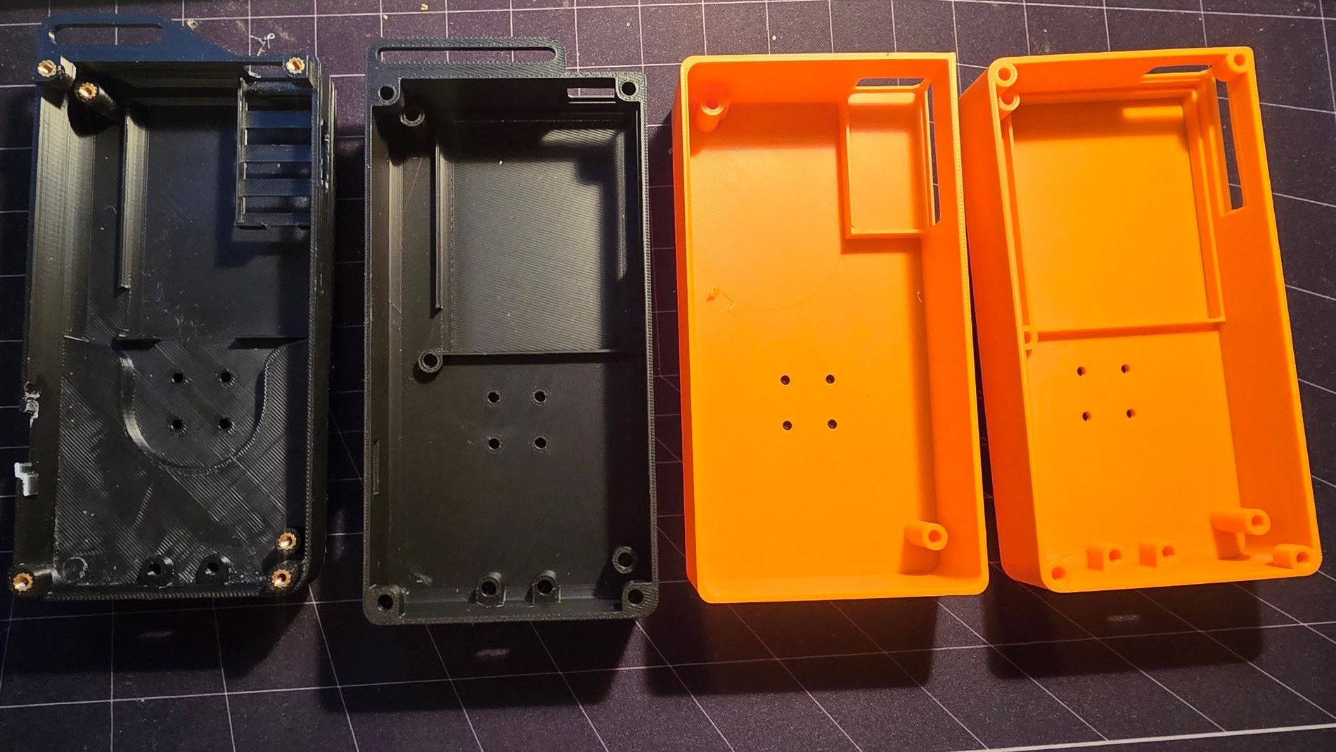 Four printed back shells side by side, two in black and two in orange